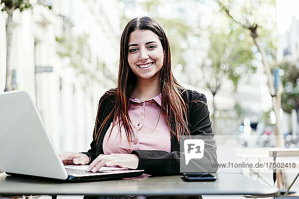 Junge Geschäftsfrau mit Laptop am Cafétisch