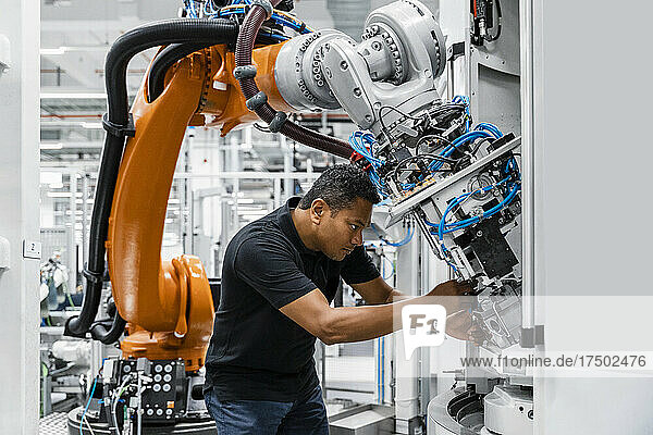 Engineer examining robotic arm in factory