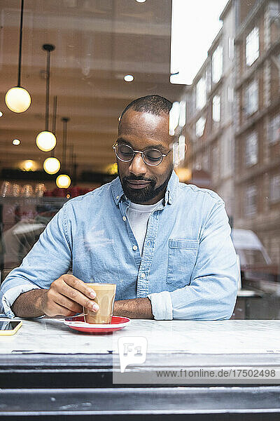 Man looking at coffee glass sitting in cafe