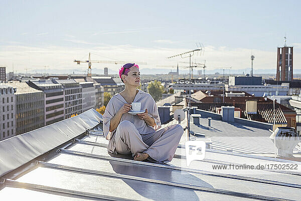 Frau trinkt an einem sonnigen Tag auf dem Dach Kaffee