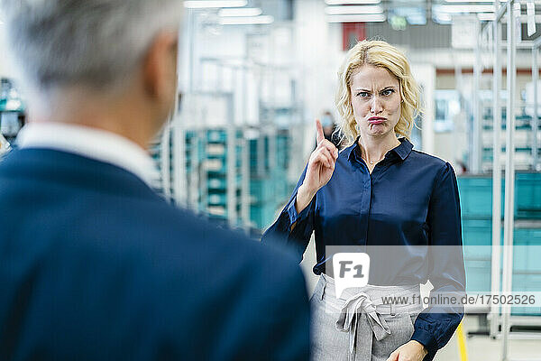 Angry businesswoman making face pointing at colleague in industry