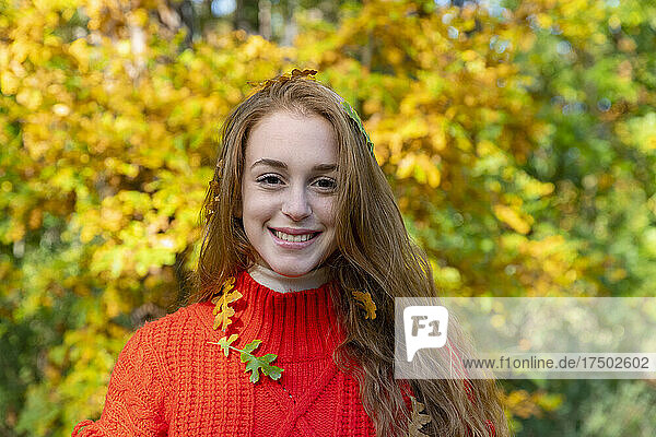 Lächelnde junge Frau mit Herbstblättern im Wald