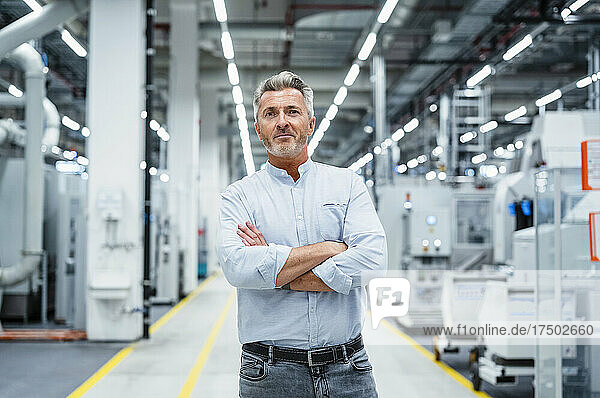 Confident businessman with arms crossed at automated industry