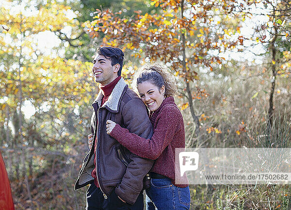 Smiling woman hugging boyfriend in autumn forest