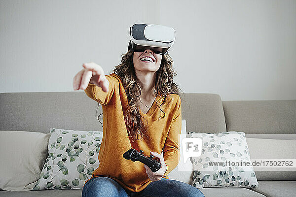 Woman with joystick gesturing wearing virtual reality headset at home