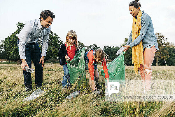 Family collecting plastic bottles after picnic in park