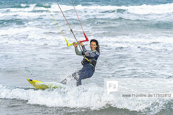 Cheerful woman surfing with kiteboard on water