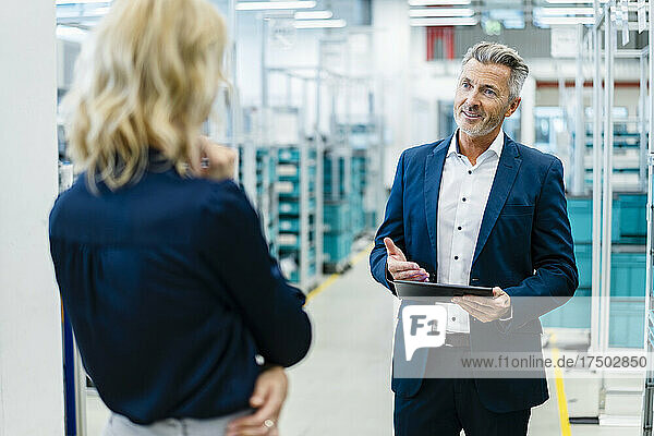 Smiling businessman having discussion with colleague at factory