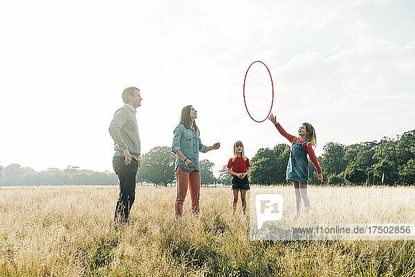 Family playing with hula hoop in park at weekend