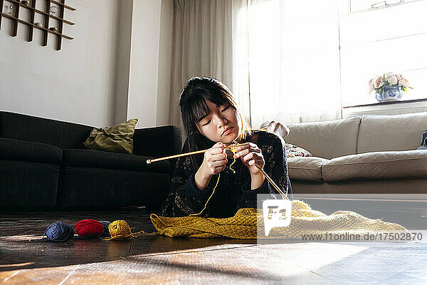 Woman knitting and relaxing on floor at home