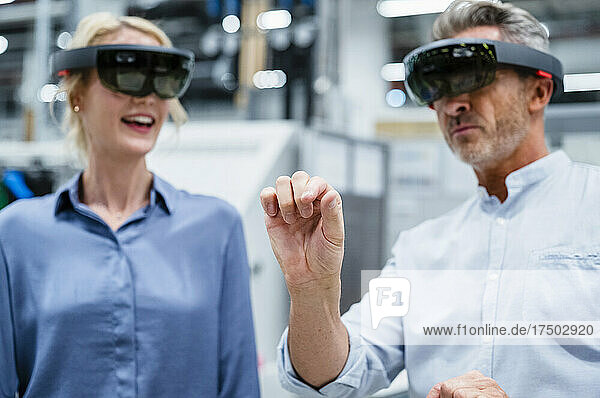 Businessman gesturing and using augmented reality eyeglasses at industry