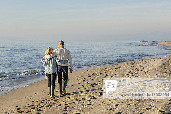Couple with arm around each other strolling at beach