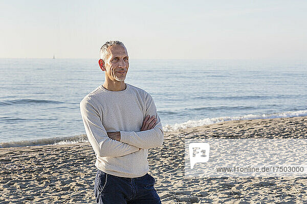 Man standing with arms crossed at beach