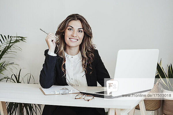 Geschäftsfrau mit Laptop sitzt am Schreibtisch im Büro