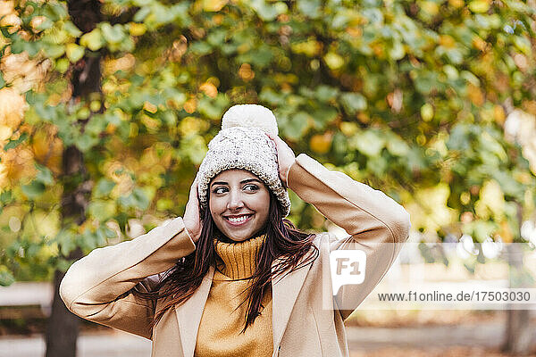Lächelnde junge Frau mit Strickmütze im Herbstpark