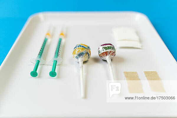 Lollipops and vaccine injections in white tray