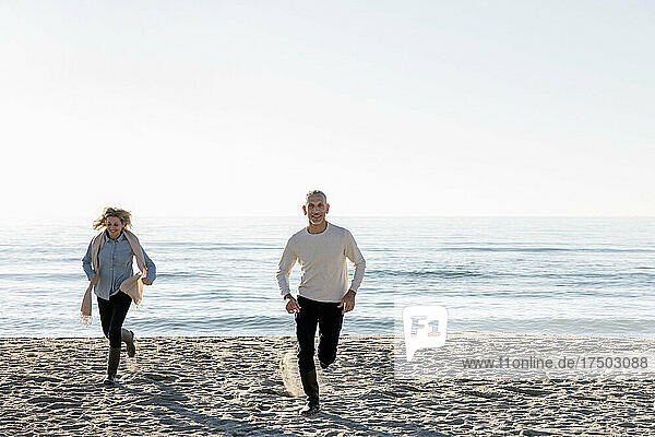 Man and woman running on sand at beach