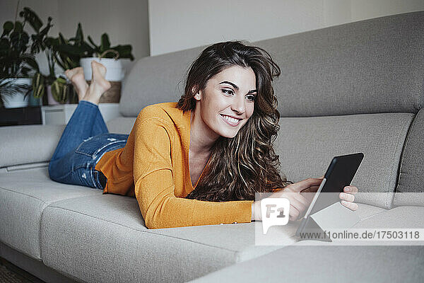 Smiling woman using tablet PC at home