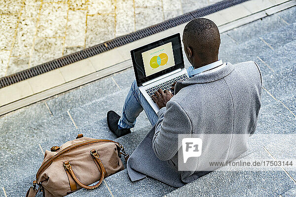 Businessman planning strategy using laptop sitting on steps