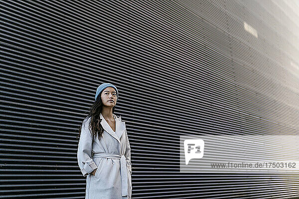 Thoughtful woman in front of black corrugated wall