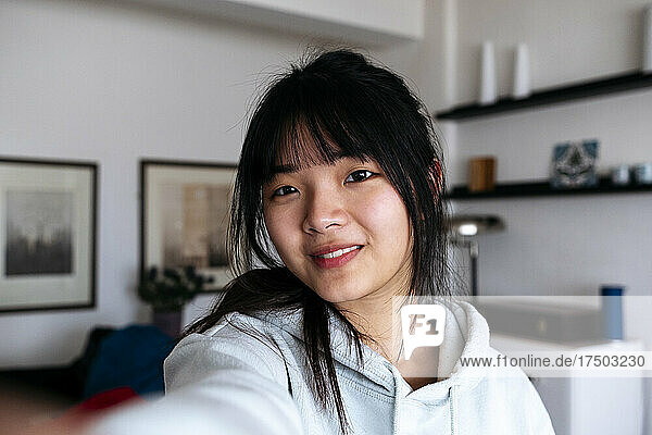 Smiling woman with bangs taking selfie at home