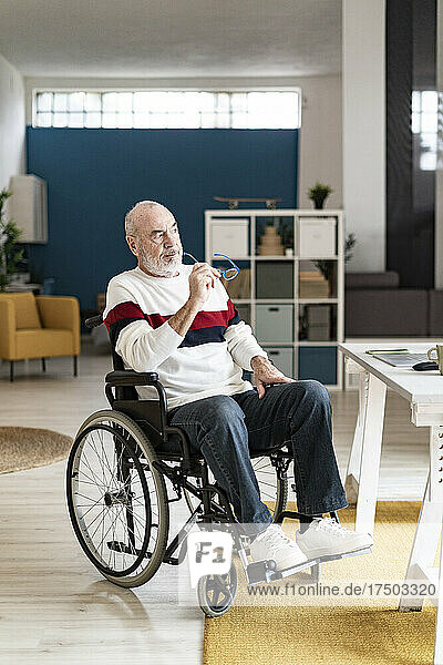 Nachdenklicher Geschäftsmann sitzt im Rollstuhl im Heimbüro