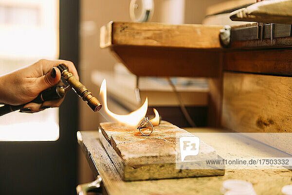 Expertin brennt in Werkstatt Silberring auf Holz