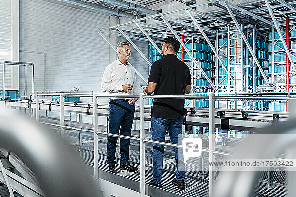 Businessman discussing with manager at warehouse railing