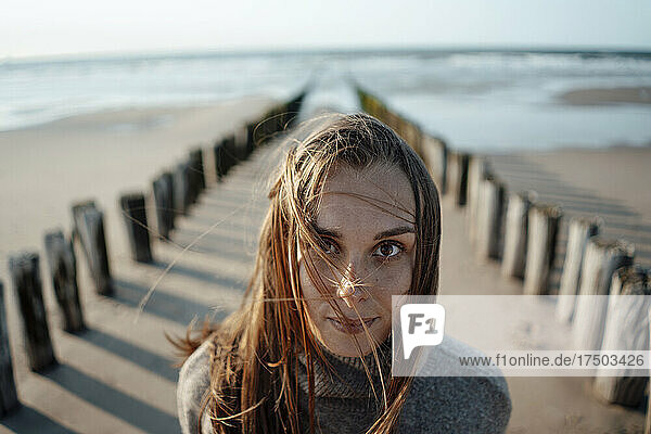 Junge Frau in der Nähe von Holzpfosten am Strand