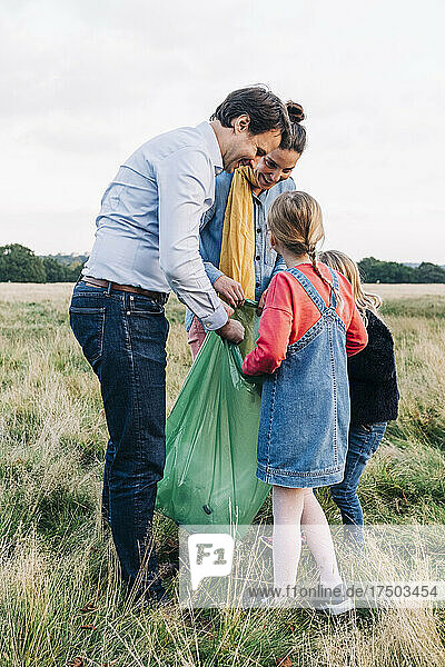 Familie sammelt nach Picknick im Park Müll in Plastiktüten