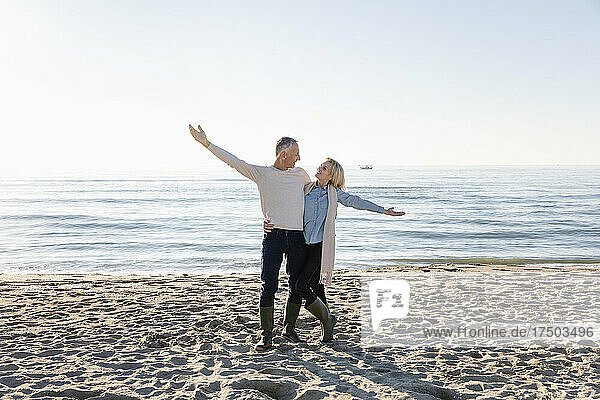 Couple with arm outstretched standing at beach