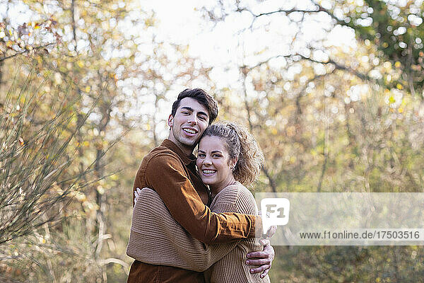 Smiling young couple hugging each other in autumn forest