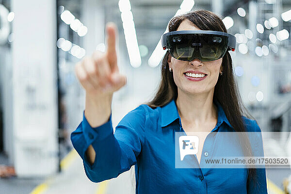 Lächelnde Geschäftsfrau mit Augmented-Reality-Brille in der Industrie