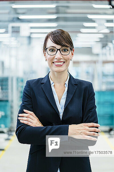 Smiling businesswoman with arms crossed at industry