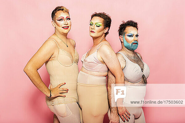 Drag queens in shapewear by pink background