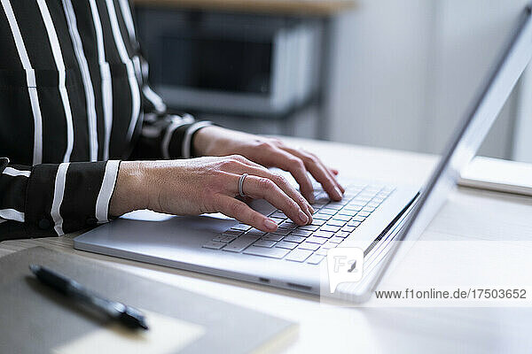 Businesswoman using laptop at home office desk