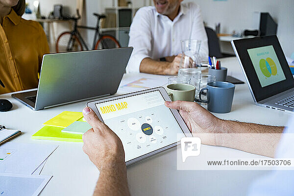 Businessman reading mind map presentation on tablet PC at office