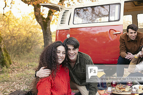 Smiling man embracing woman in autumn forest