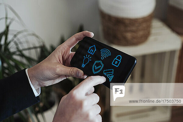 Businesswoman holding smart phone with home automation icons