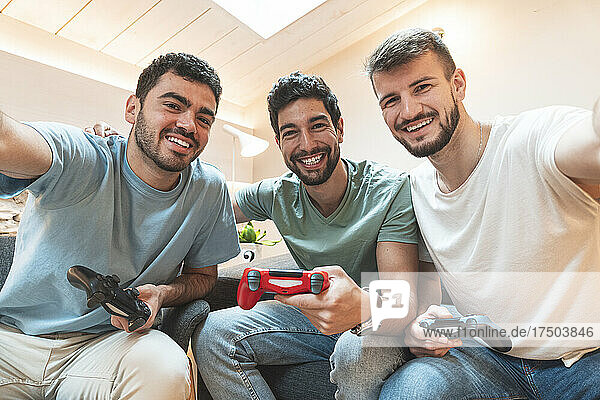 Happy friends with controllers taking selfie at home