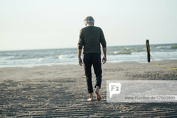 Man walking towards sea at beach