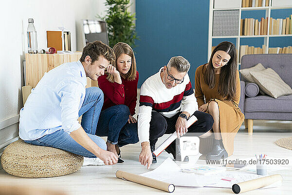 Businessman pointing at documents with colleagues crouching on floor in office