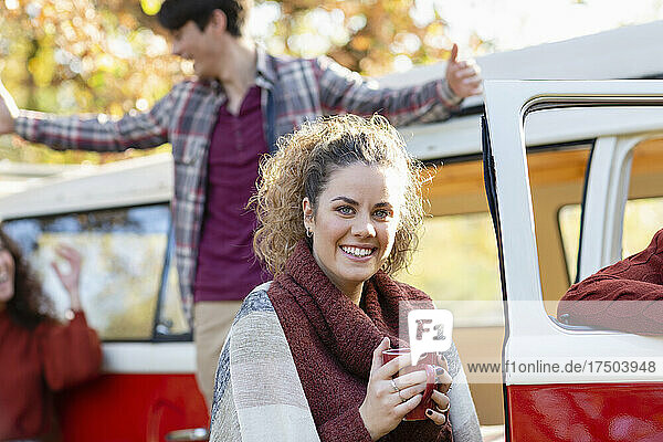 Smiling woman having coffee with friends having fun in background on weekend