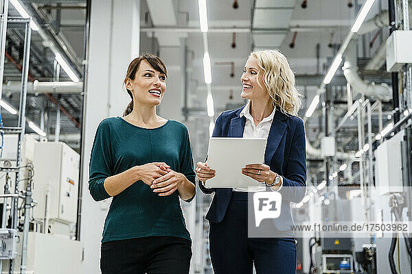 Smiling businesswomen discussing at modern factory