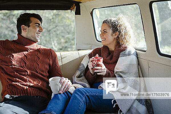 Glückliches Paar beim Kaffeetrinken im Van am Wochenende