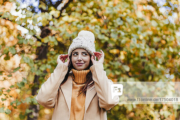 Lächelnde Frau mit Strickmütze im Herbstpark