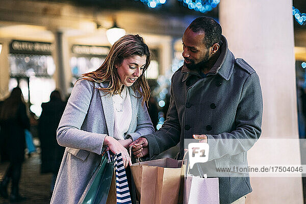 Woman discussing with man holding shopping bags at Christmas market