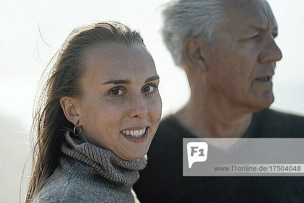 Daughter in turtleneck with father at beach