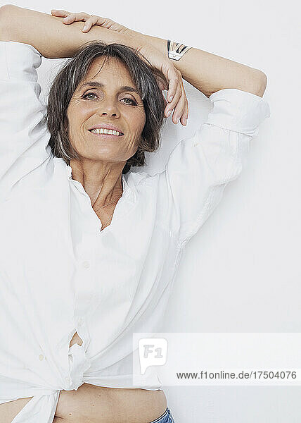 Smiling mature woman with arms raised against white background