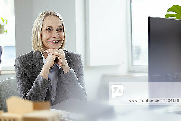 Thoughtful businesswoman with hands on chin at desk